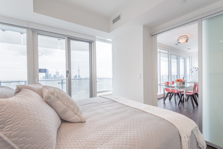 Image of bedroom with glimpse of kitchen and Toronto skyline