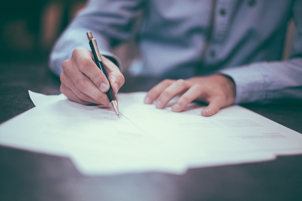 Man holding pen and signing paper.