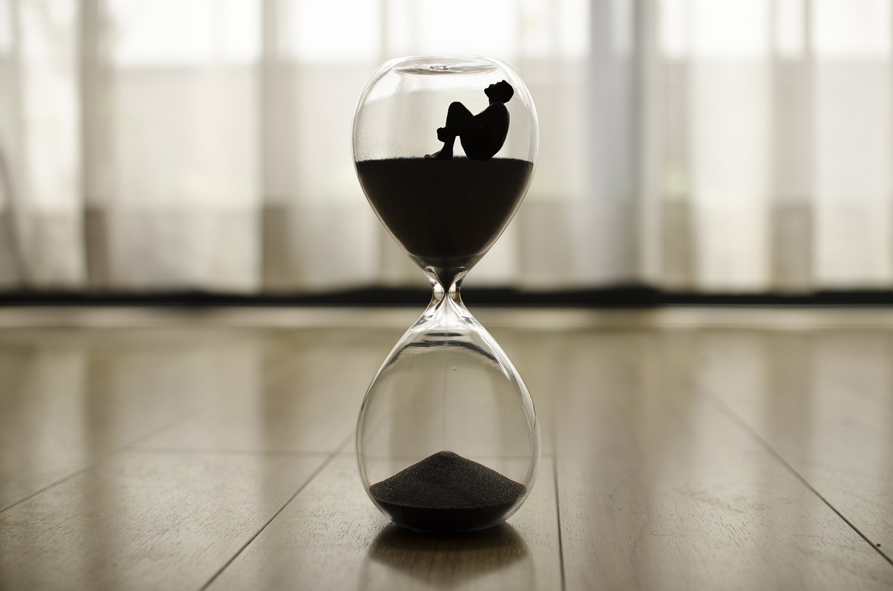 Man sitting inside hourglass on house floor.