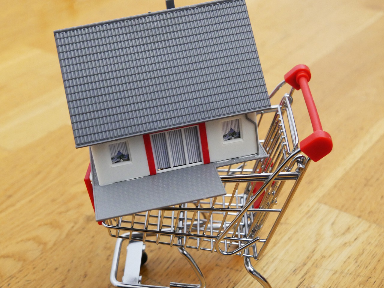 Miniature house in shopping cart showing June 2022 buyer's market.