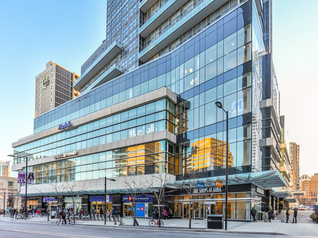 Photo of 384 Yonge Street from distance. View shows so many windows, almost blue in colour, in addition to people and also bicycles.