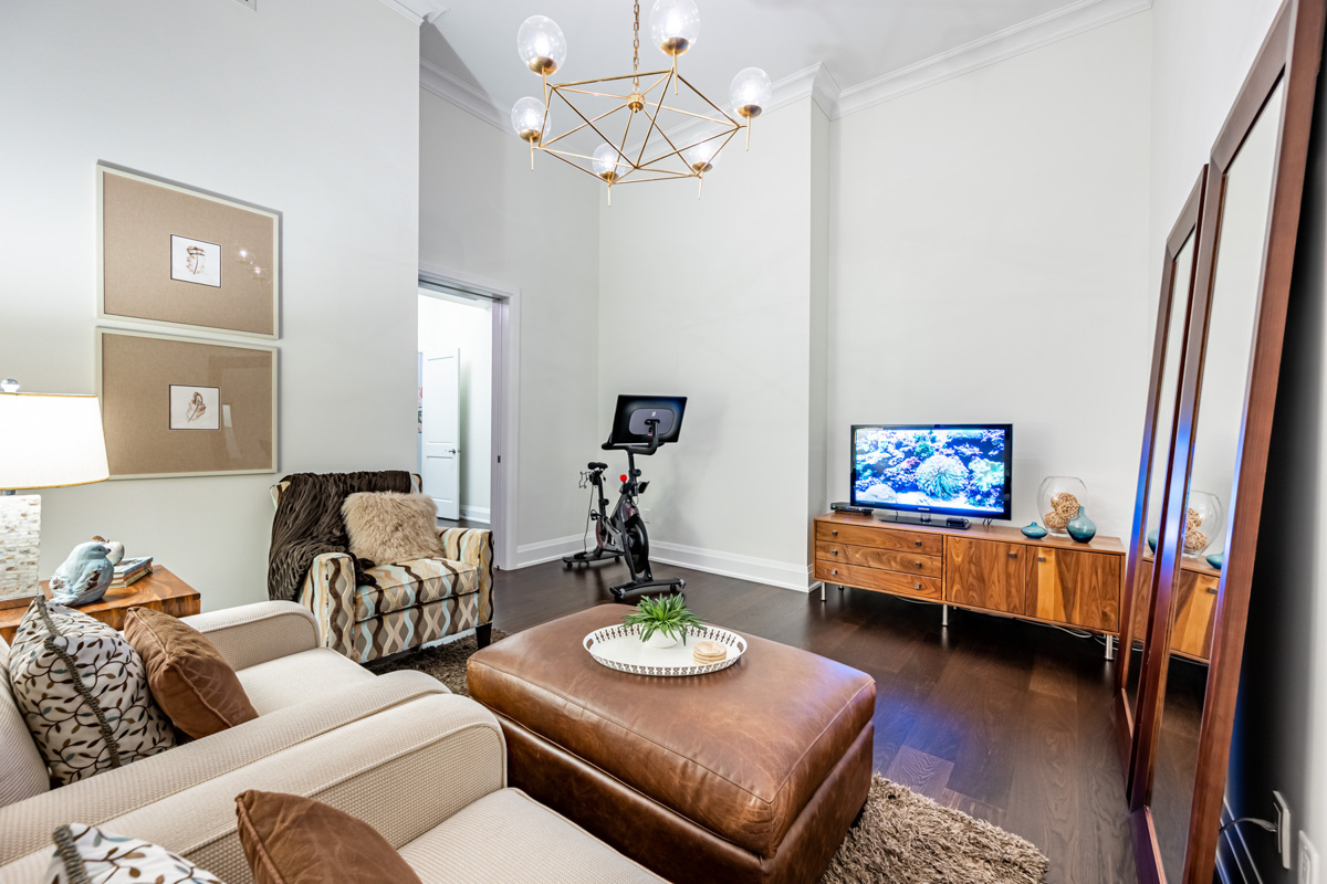 Condo bedroom with hardwood floors, crown moulding and chandelier.