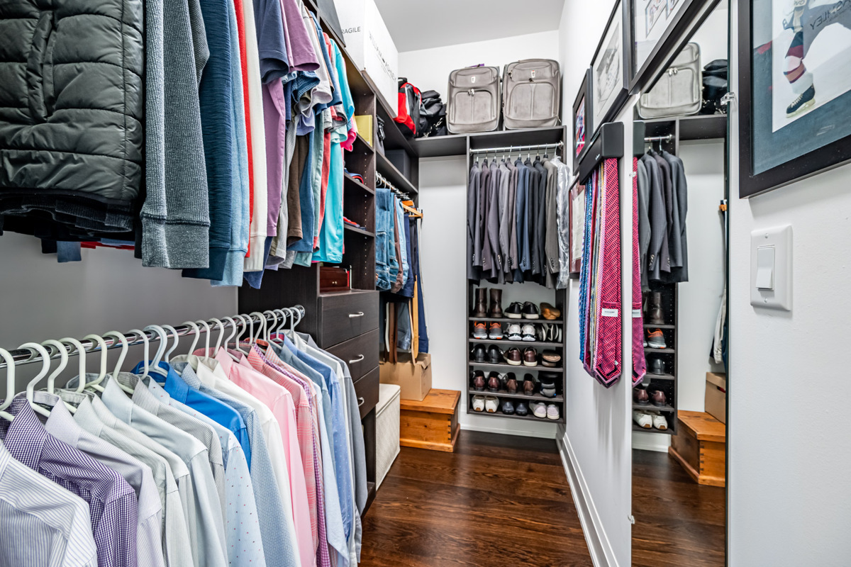 Walk in closet with clothes and luggage.