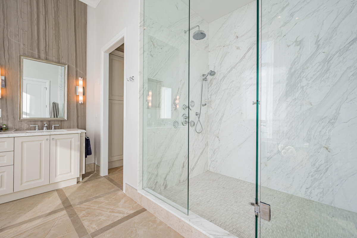 Walk-in shower with glass doors and white tiles.