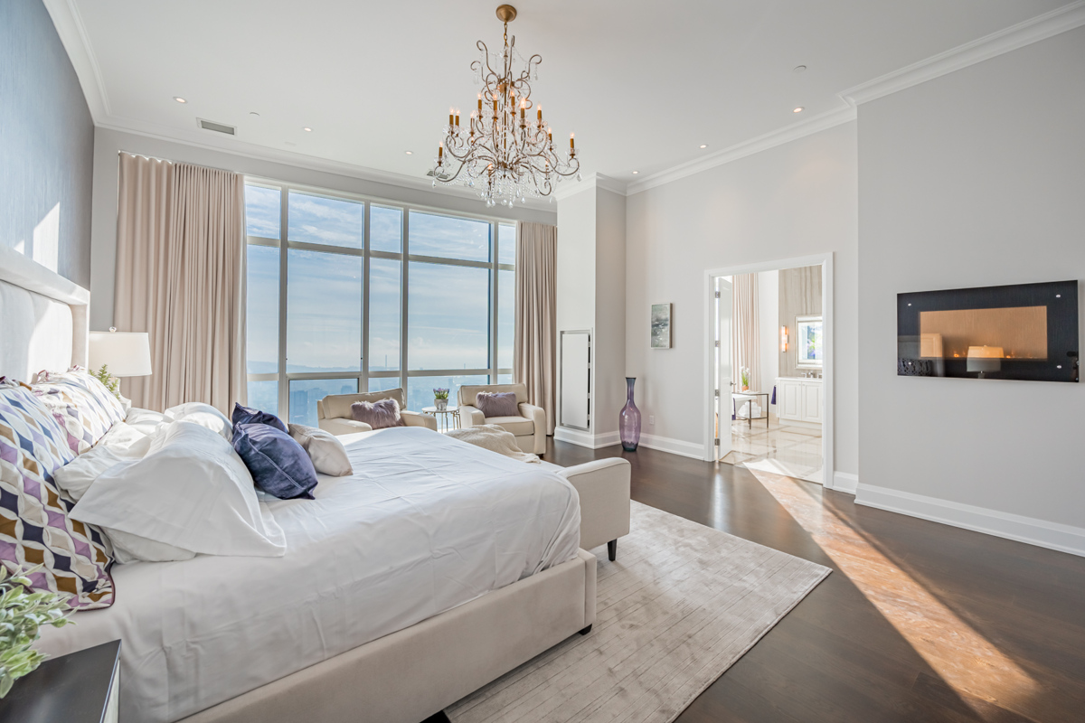 Condo bedroom with hardwood floors, crown moulding and electric fireplace.