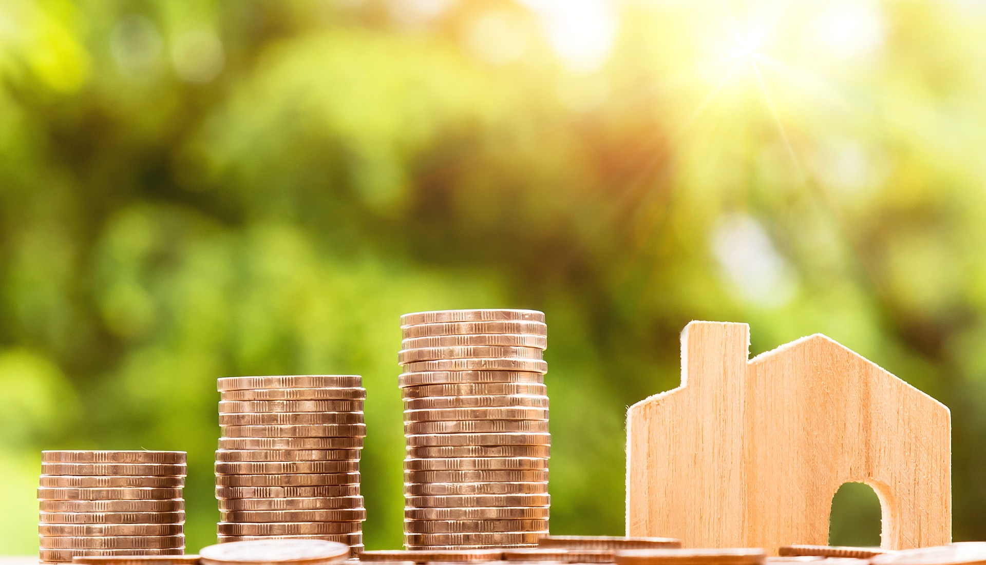 Image of money depicting a stack of coins and miniature wooden house, illustrating tax savings