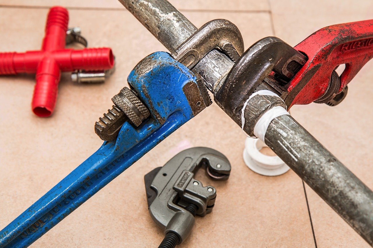 Close up of red and blue wrenches being used for plumbing.