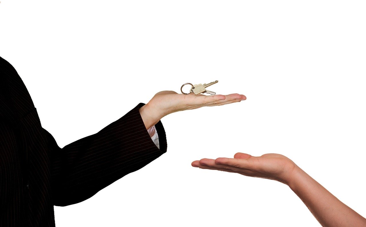 Close up of male hand holding house keys and female hand with palm facing upwards