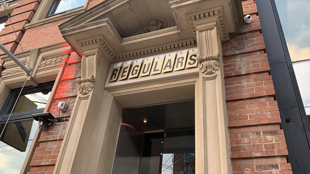 exterior of Regulars Bar with beige columns - King West Toronto.