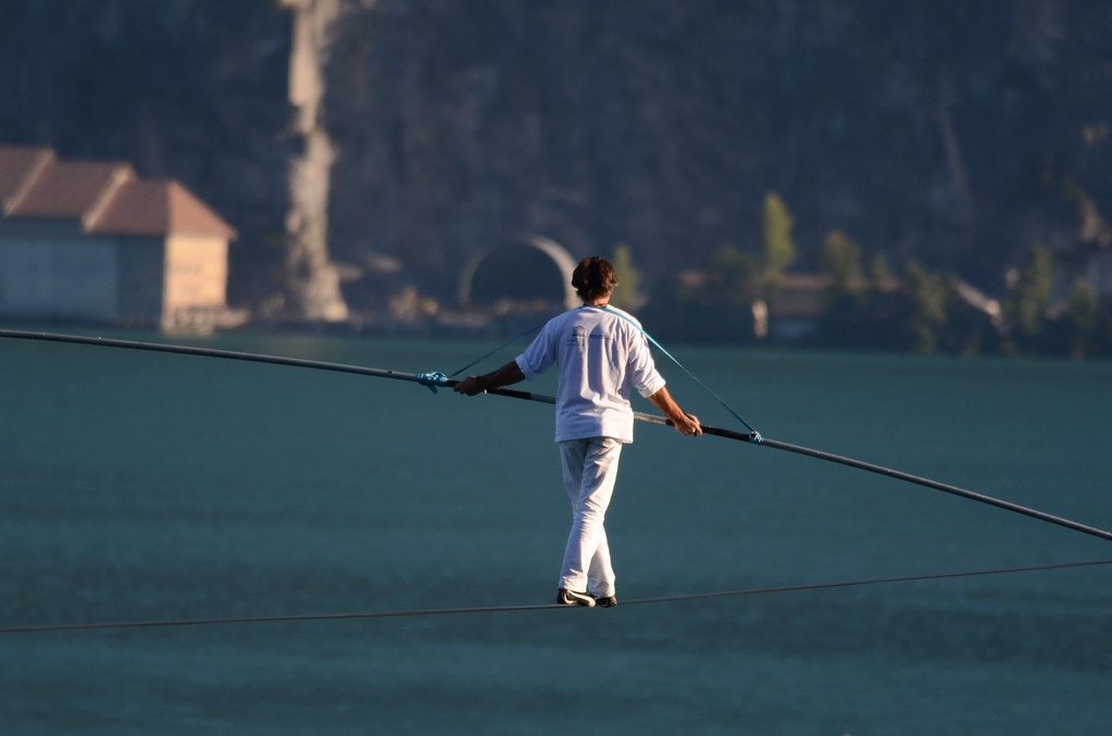 Tightrope walker crossing lake.