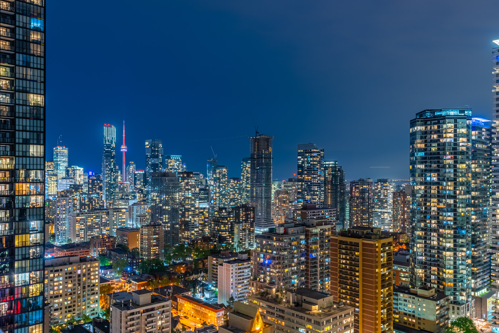 Toronto skyline at night with CN Tower lit up red in distance.