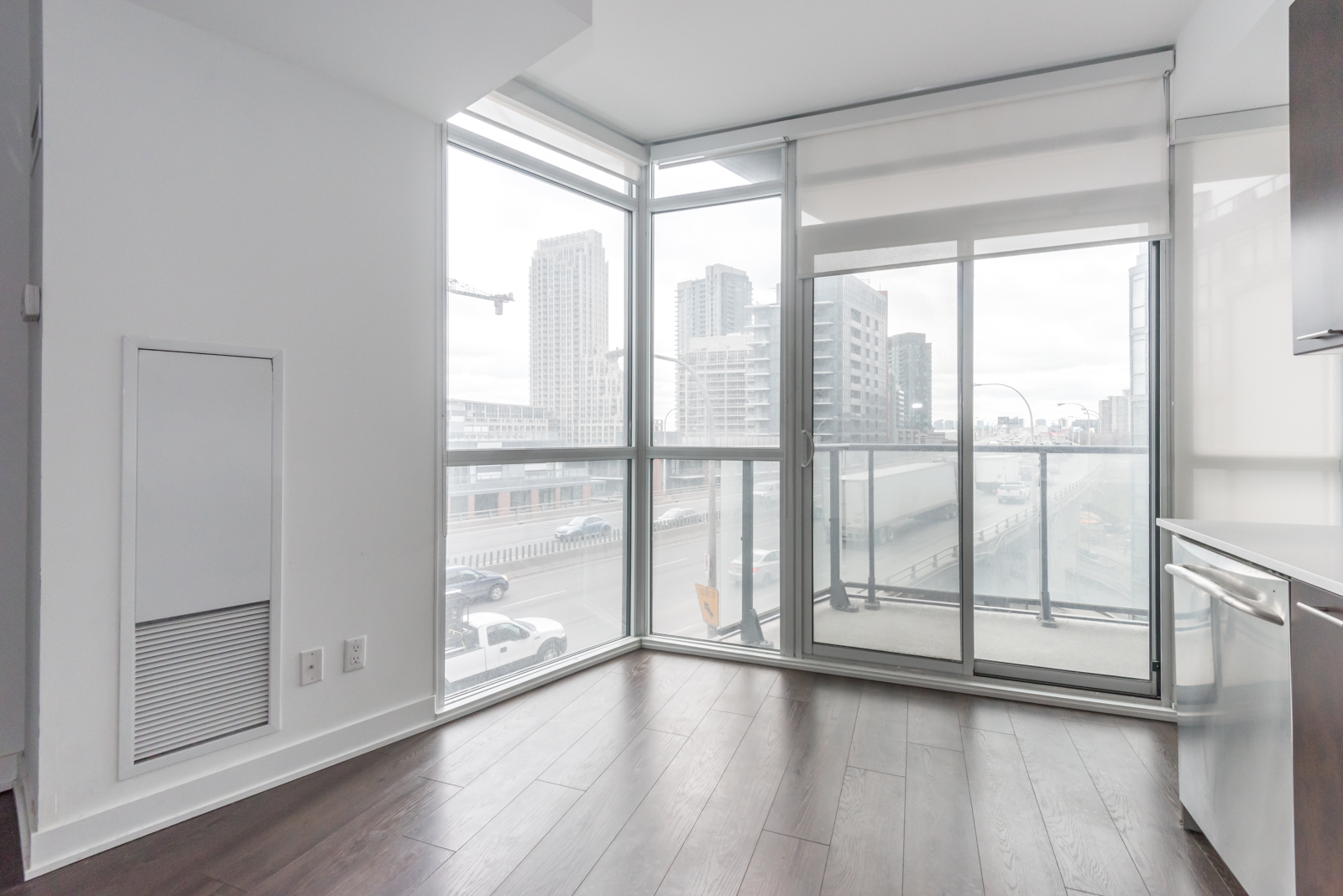 This photo shows the condo's large windows and so much of the city beyond. There's also blinds for privacy. Furthermore, we can see the balcony and yet another gorgeous view of Toronto.