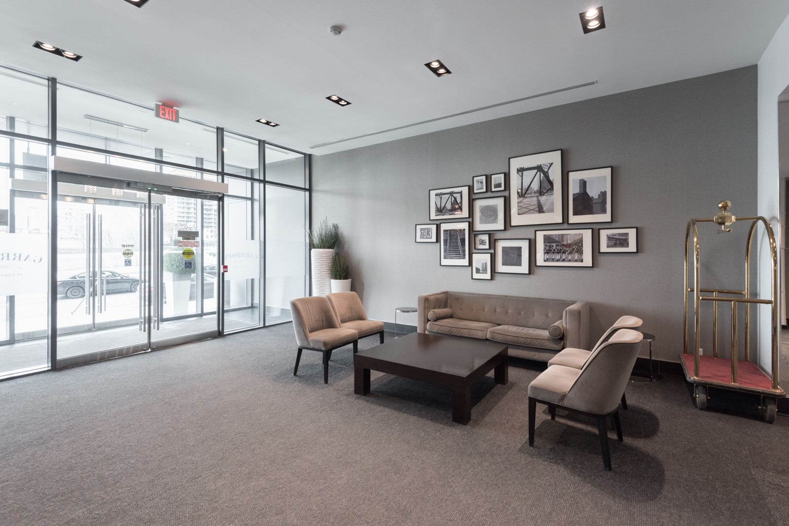 Picture showing 169 Fort York lobby. We can see chairs, a table, and a rather large number of art.