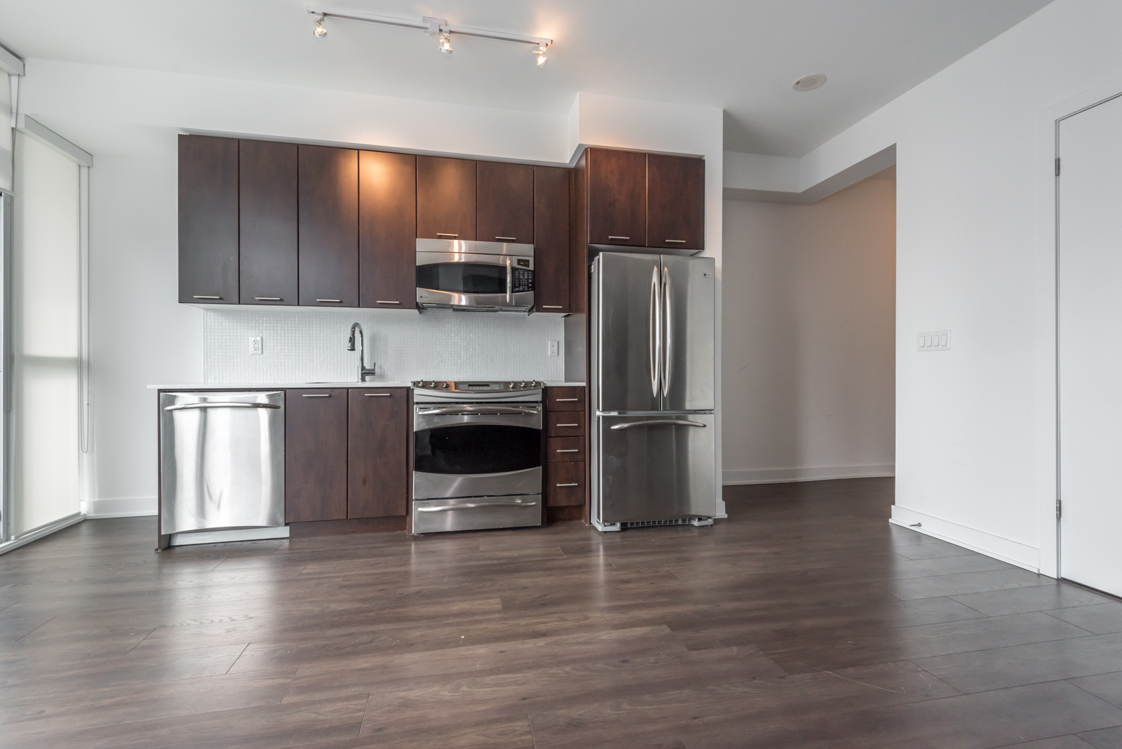 Photo of 169 Fort York kitchen. First of all, we can see so many appliances. Another highlight is the colours, and finally, the laminate floors.