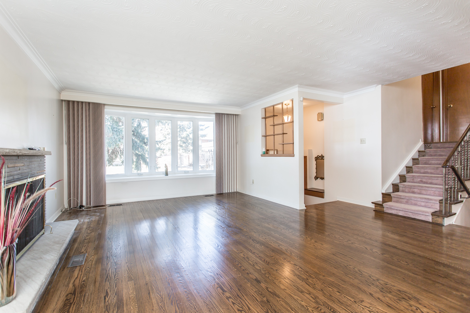 Image shows living room, hardwood floors, and rather wide windows.