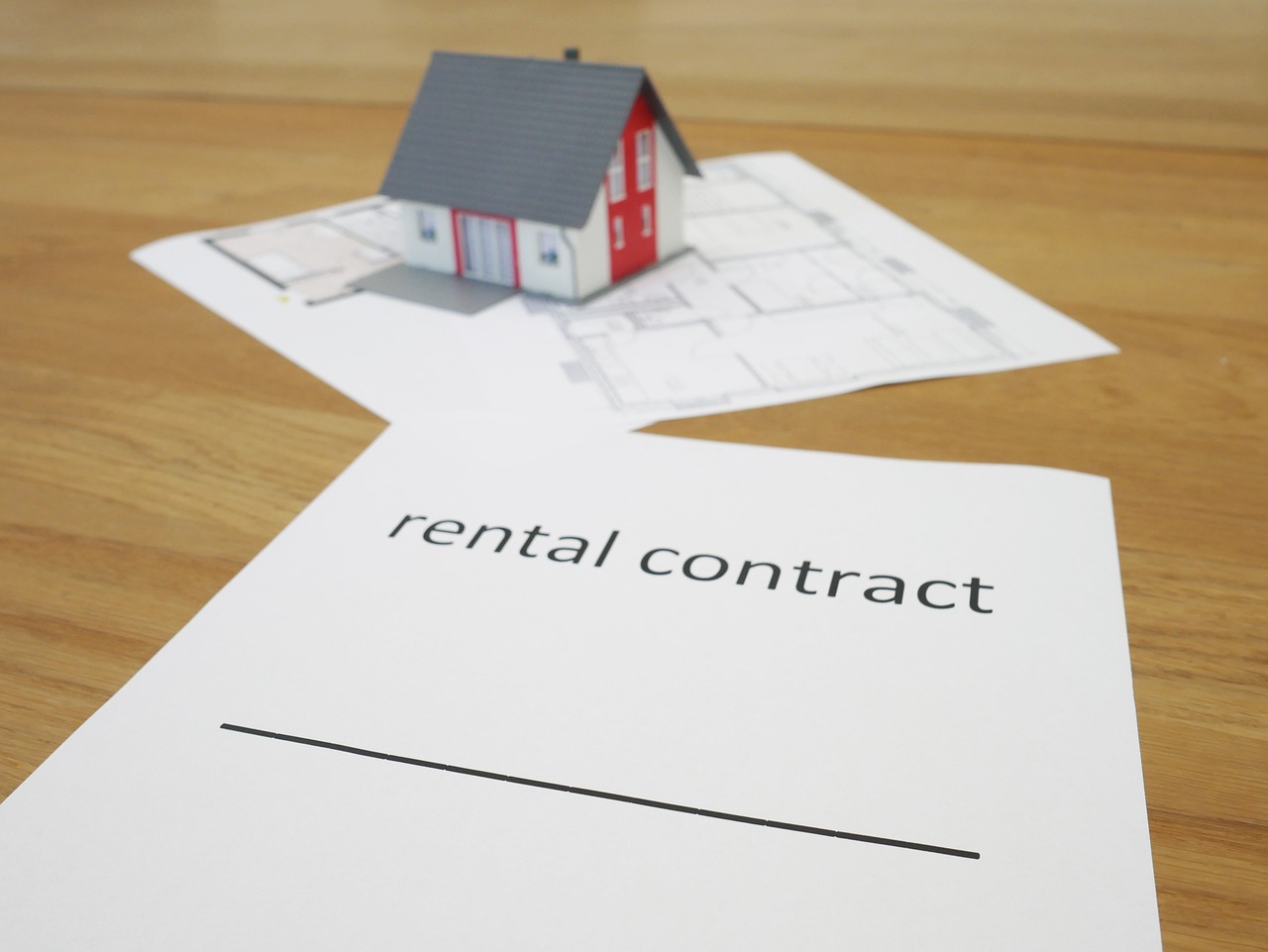 White rental contract paper with miniature house.