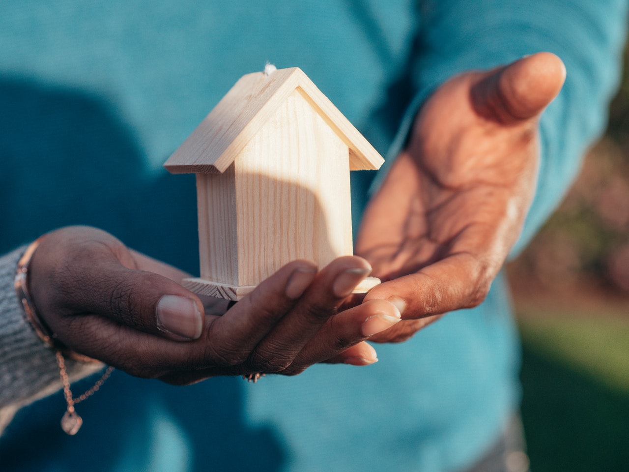 Close up of miniature wood home being held by African American couple.