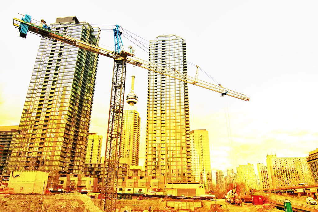 Construction crane and buildings in downtown Toronto in yellow filter.