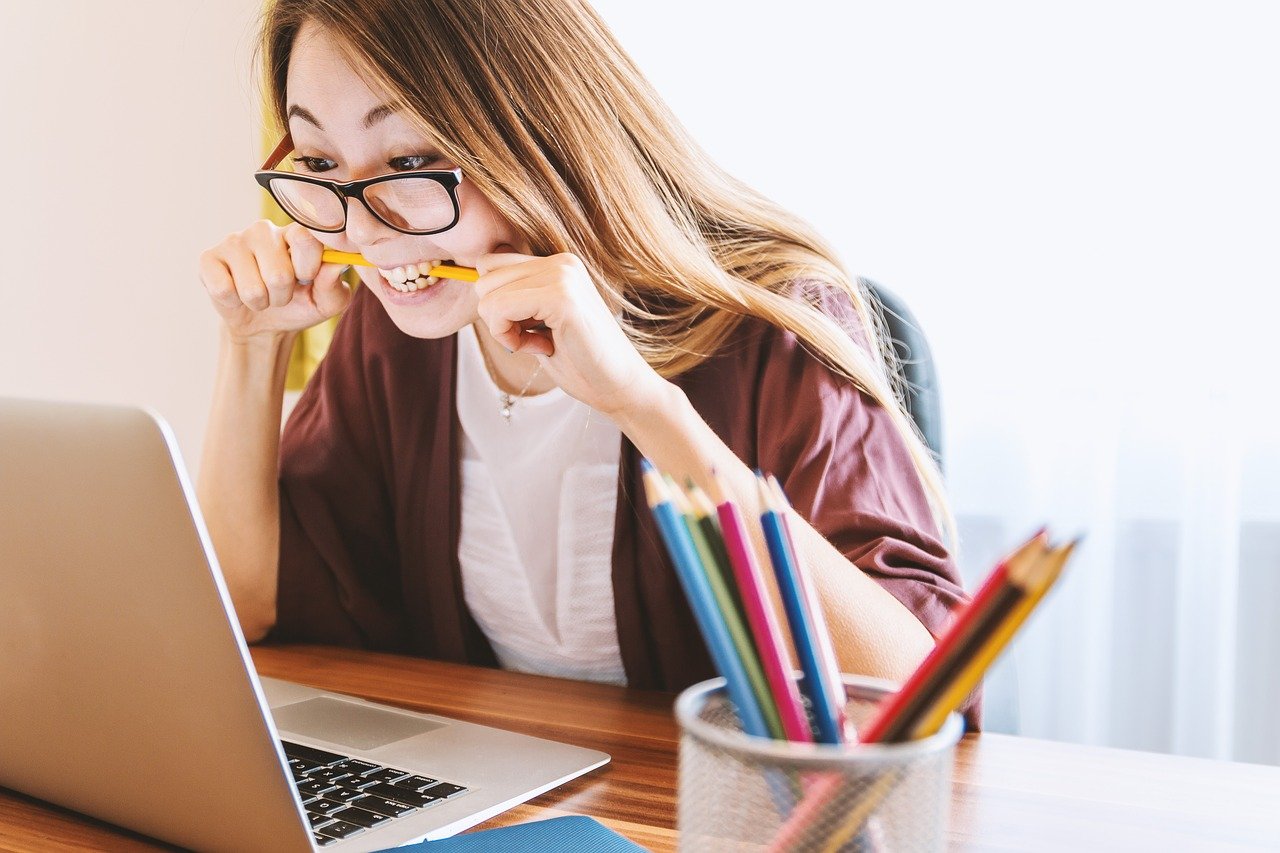 Young woman biting pencil to show anxiety over new mortgage stress test.