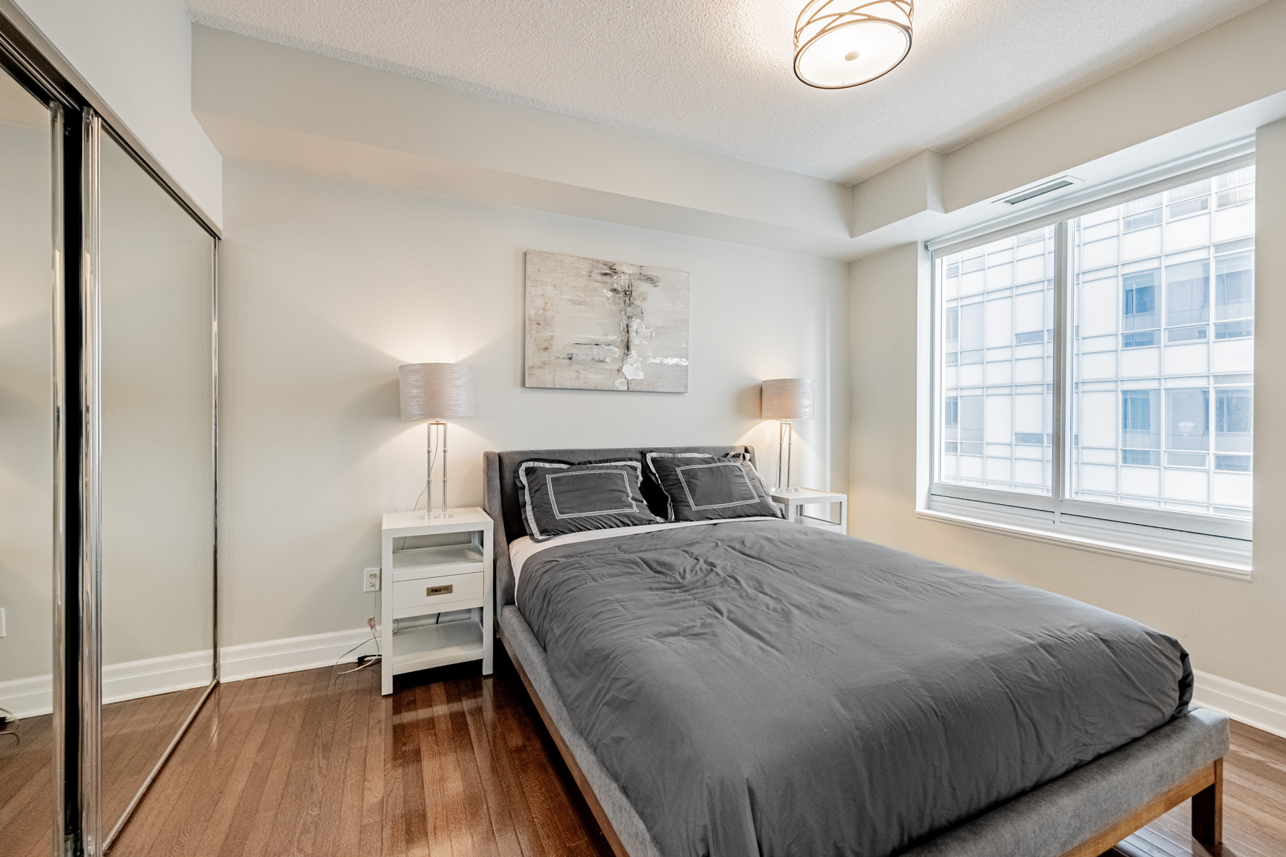 Large primary bedroom with hardwood floors and mirror door closet – 35 Balmuto St Unit 1209.