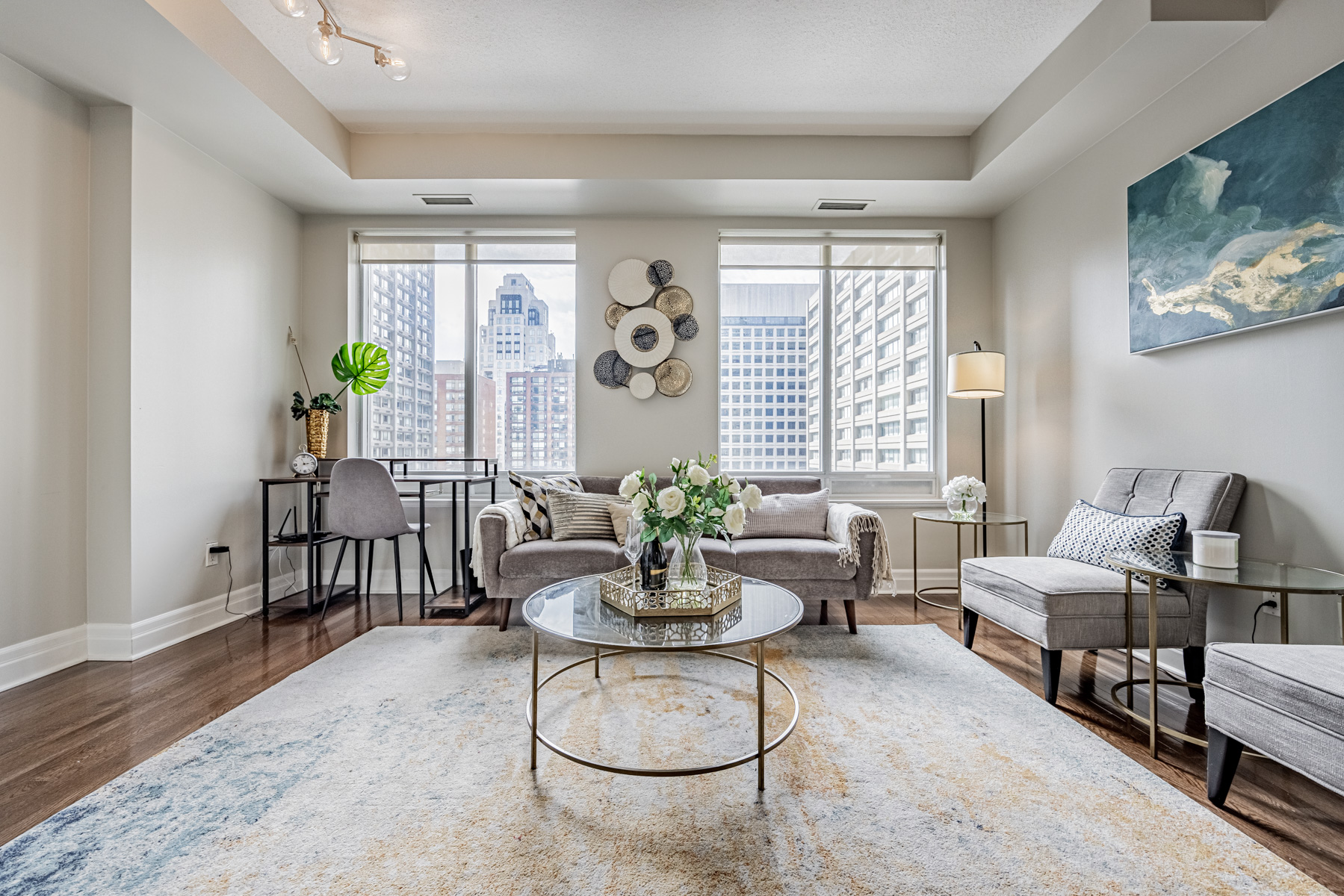 Condo living room with sofa, chairs, tables and corner desk.