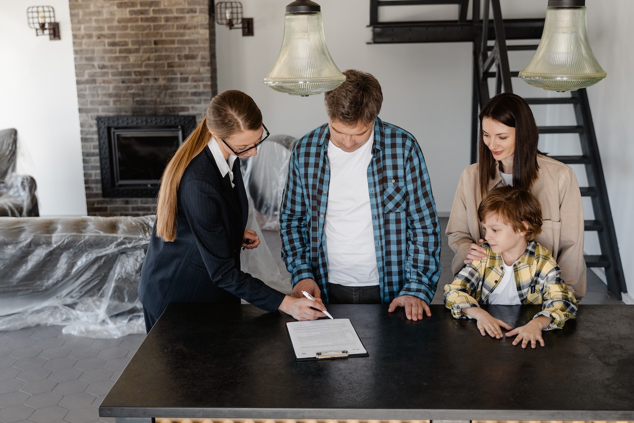 Family gathered together as father signs document.