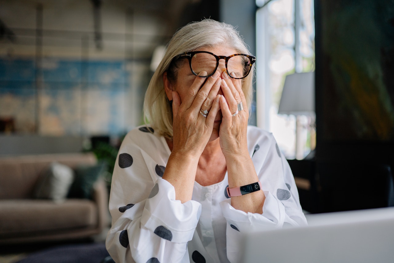 Elderly woman covering face due to stress of probate.