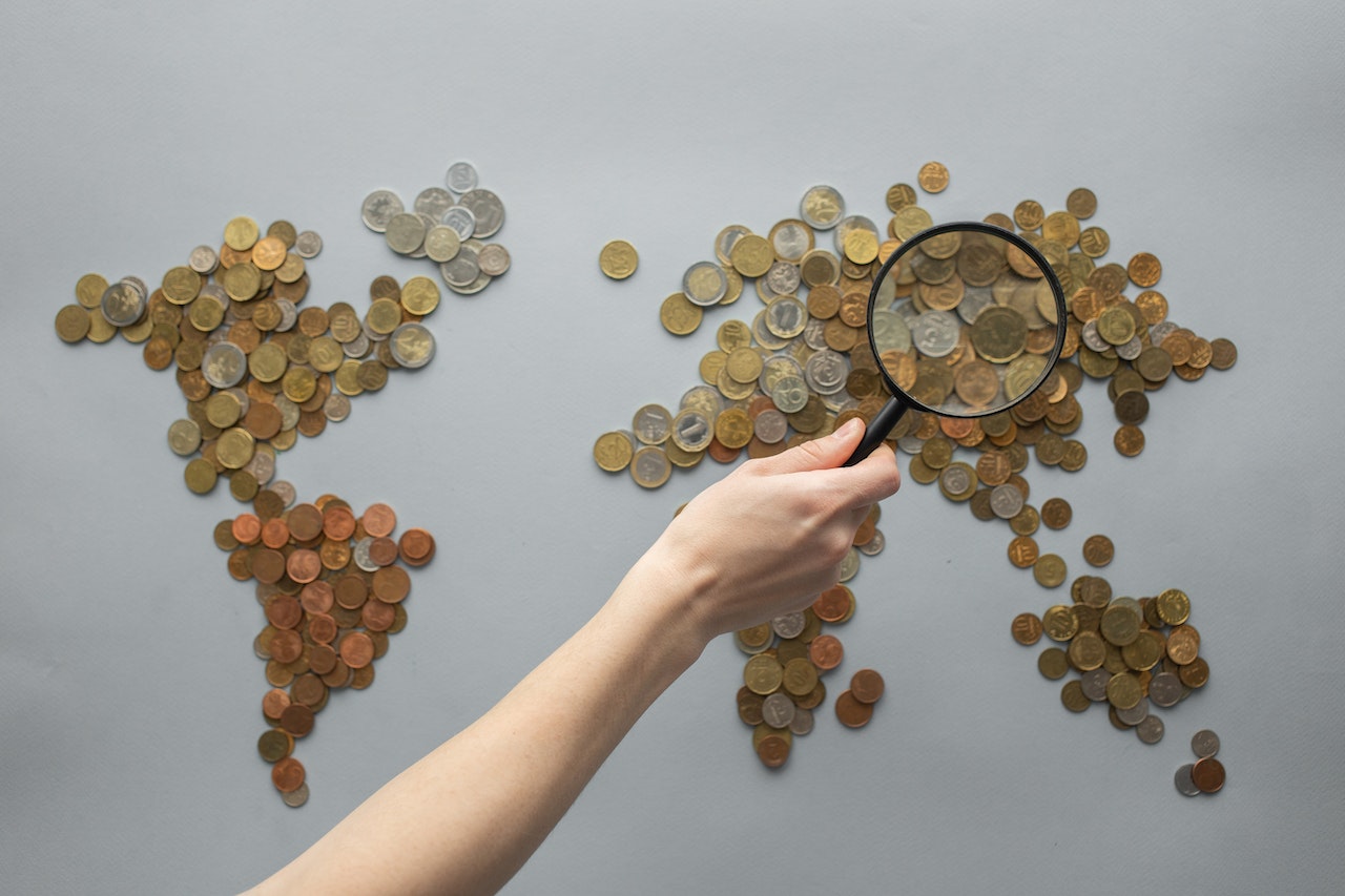 Magnifying glass over world map made of pennies to show NRST rebate.