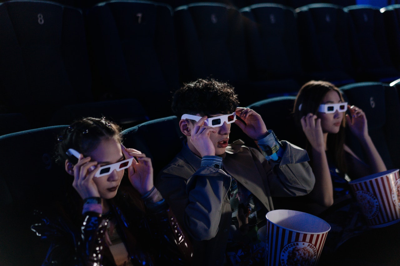 Young people putting on 3D glasses in movie theatre.