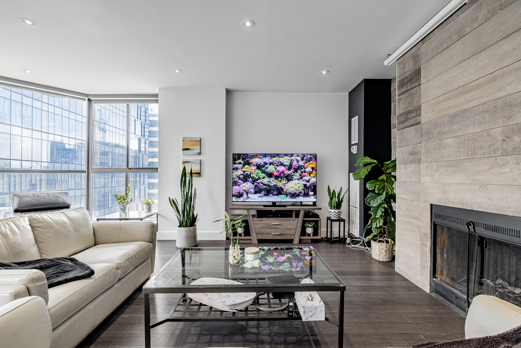 Penthouse living room with fireplace, TV, furniture and plants.