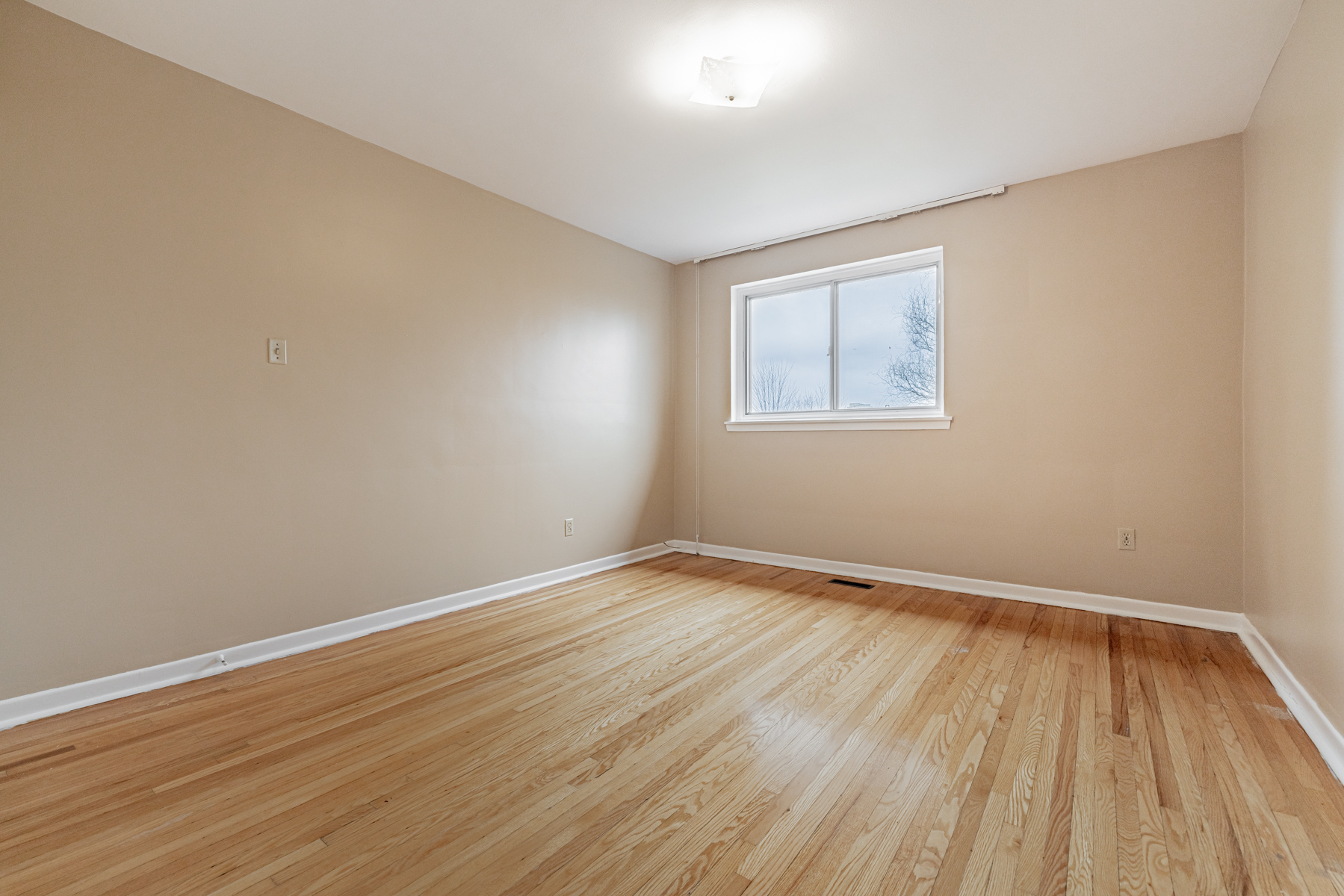 Empty bedroom with window overlooking park.