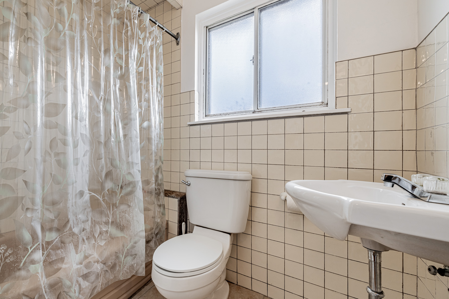 4-piece bath with ceramic tiles, tub and sink.