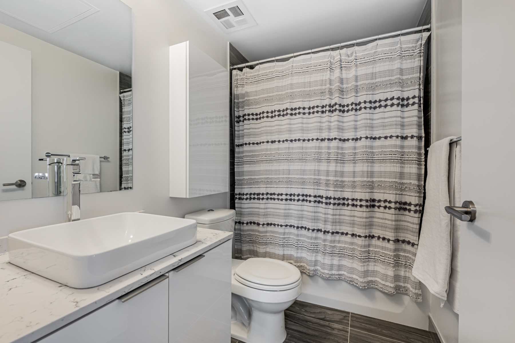 Condo bath with quartz counters, raised basin, cabinet, and soaker tub – 11 Wellesley St Unit 5808.