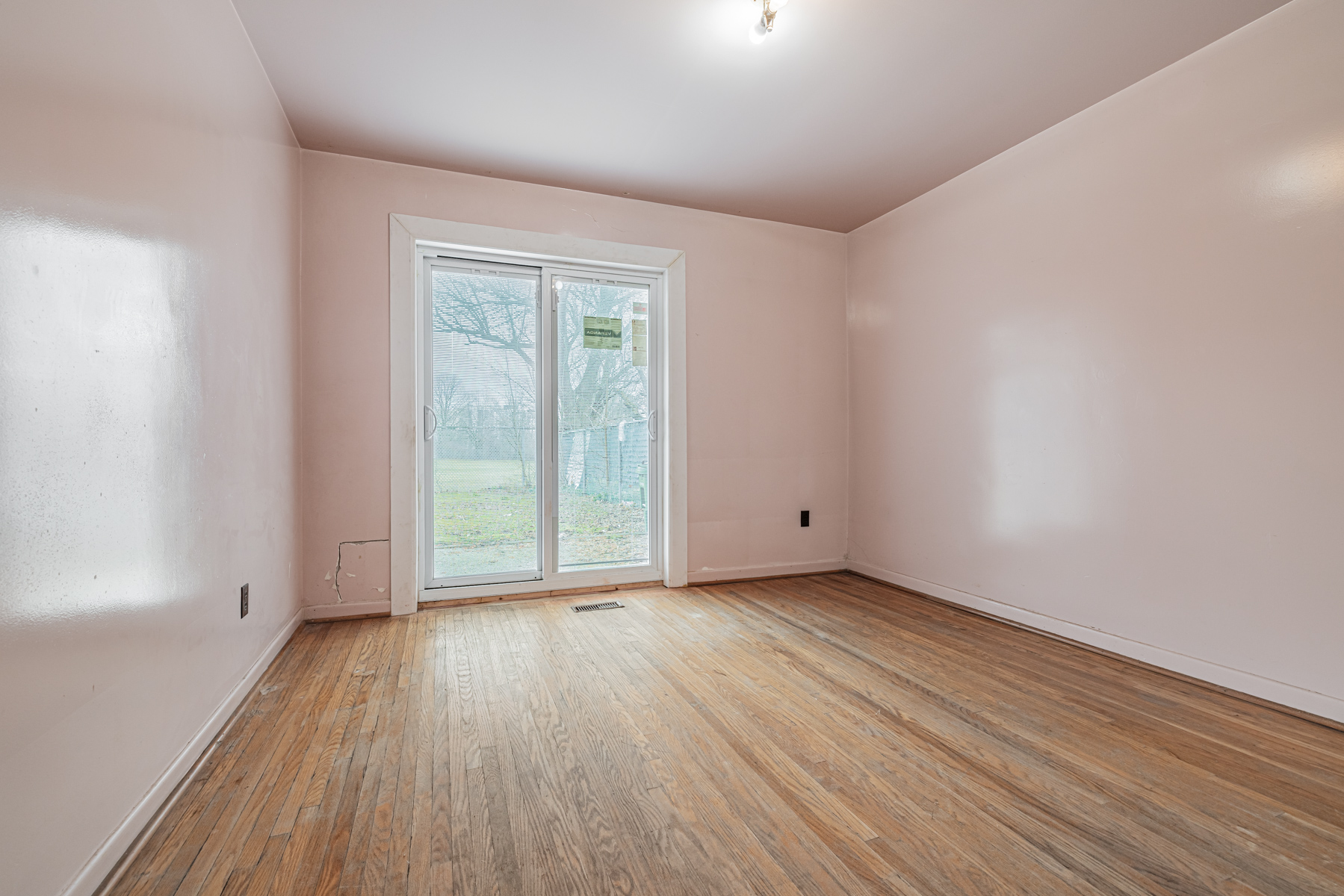 1 Stong Court – 3rd bedroom with dark hardwood floors, pink walls and door to backyard.