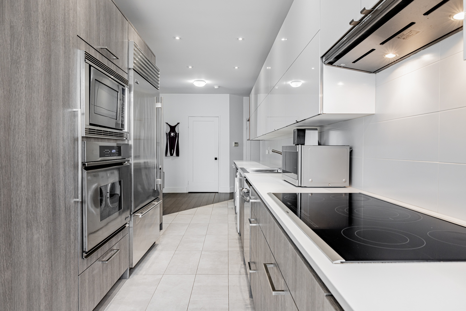 Beautiful condo kitchen with white granite counters, glossy cabinets and pot-lights.