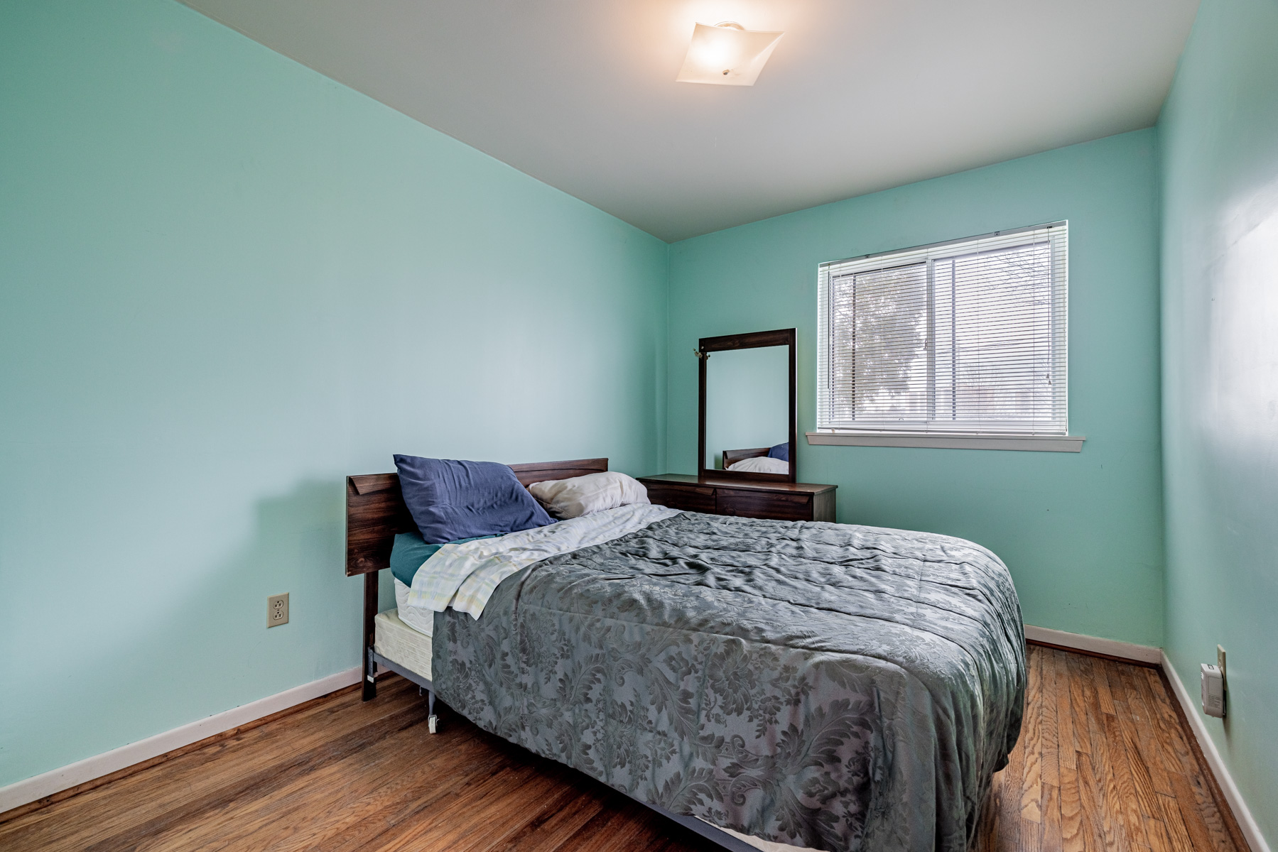 House bedroom with vibrant blue walls and large bed.