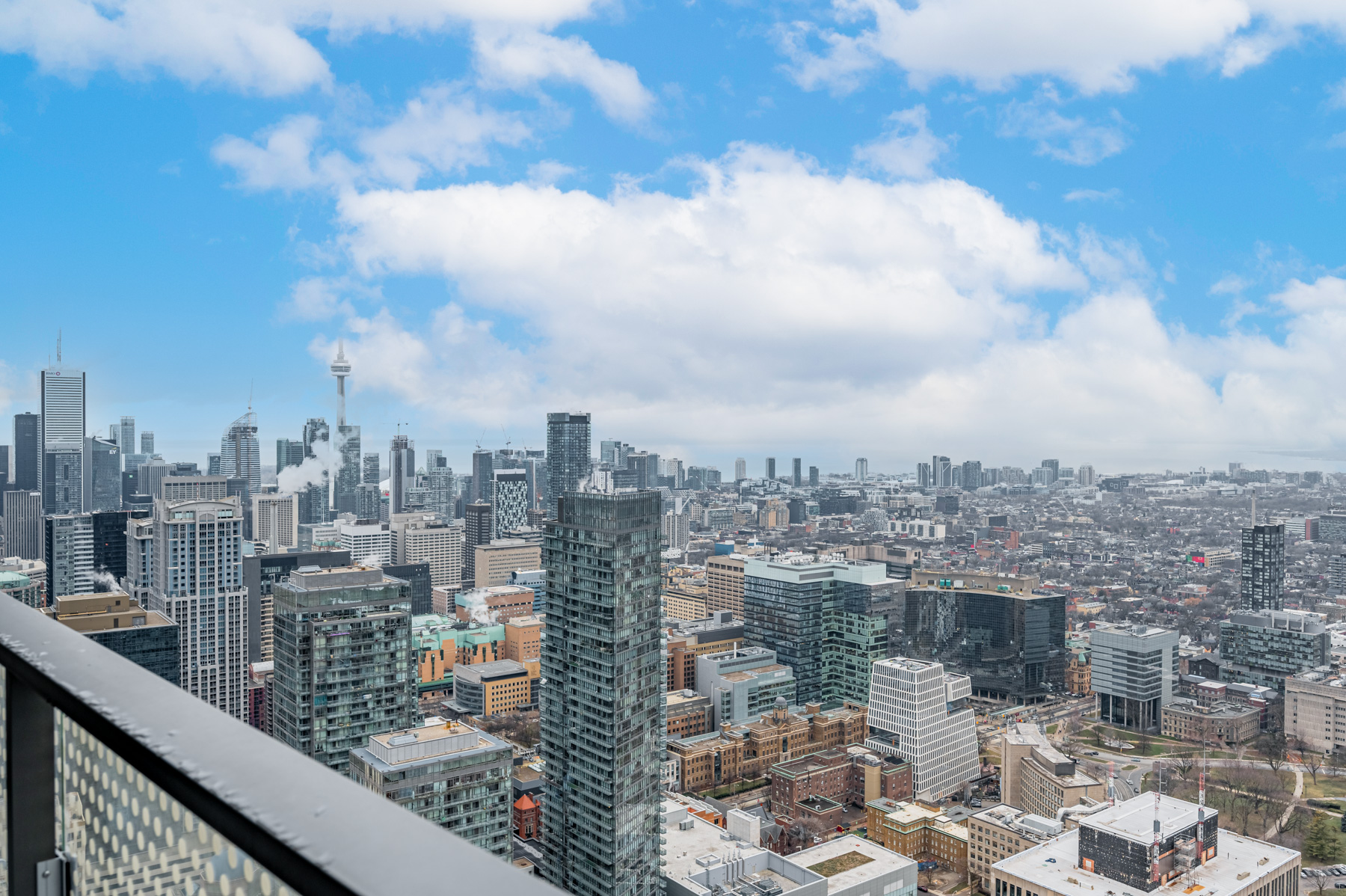 View of cloud-covered CN Tower in distance from condo balcony.