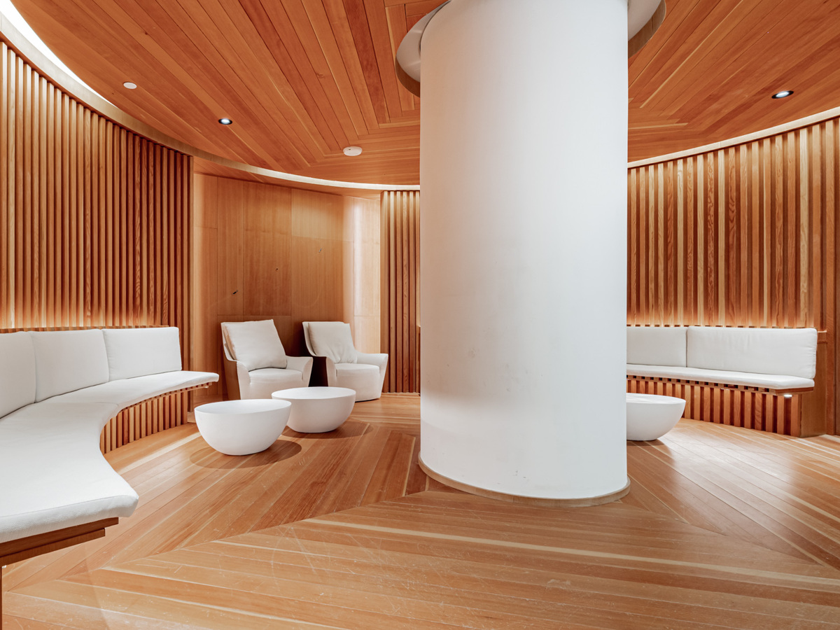Condo meditation room amenity with round shape, wood panels and white furniture and pillar.
