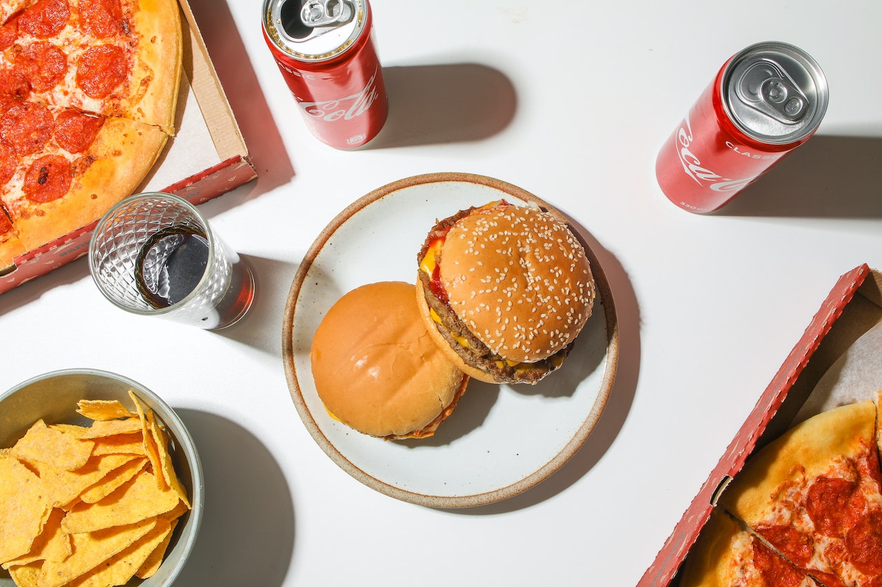 Burger, fries, pizza, Coke cans from McDonald's.