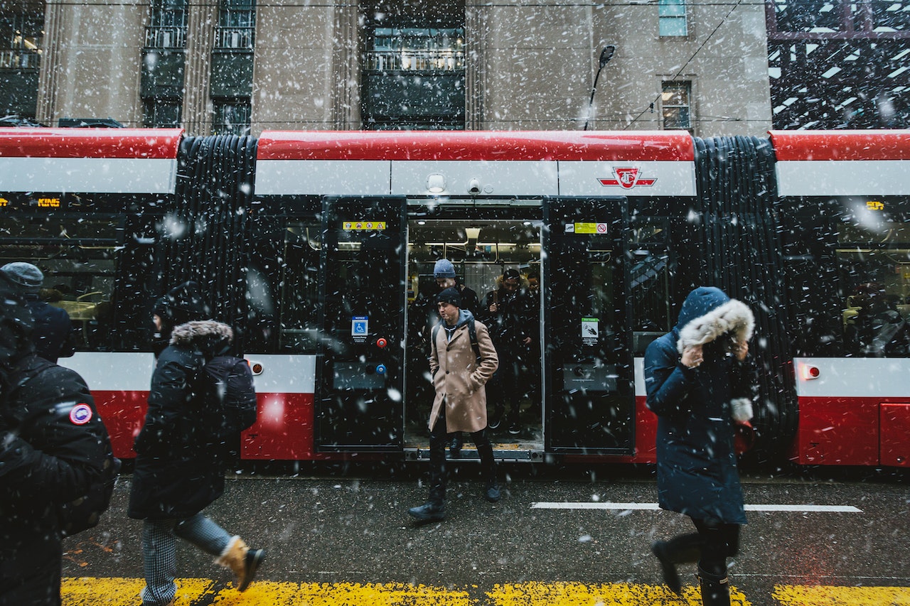 Man stepping off red TTC streetcar in winter.