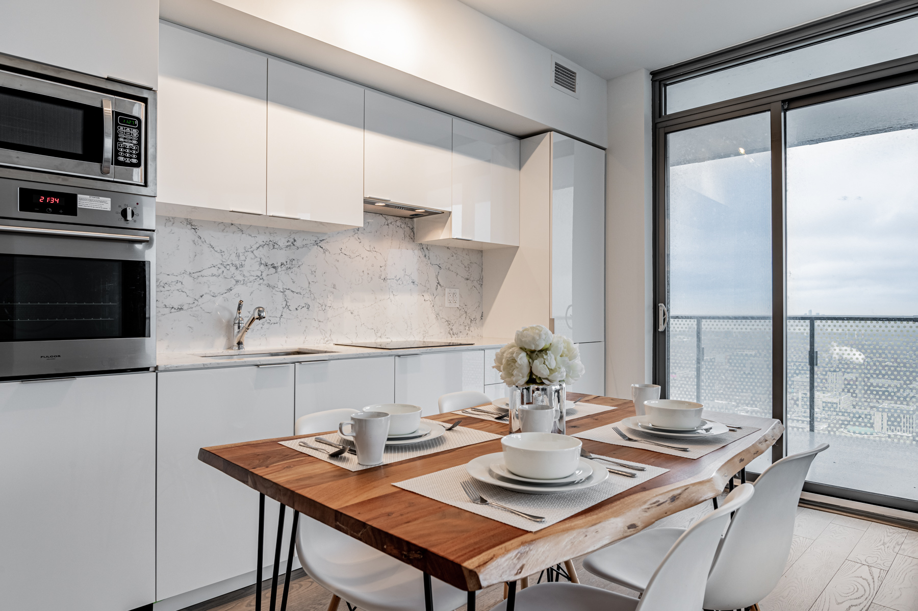 Condo kitchen with white cabinets, counters and backsplash.