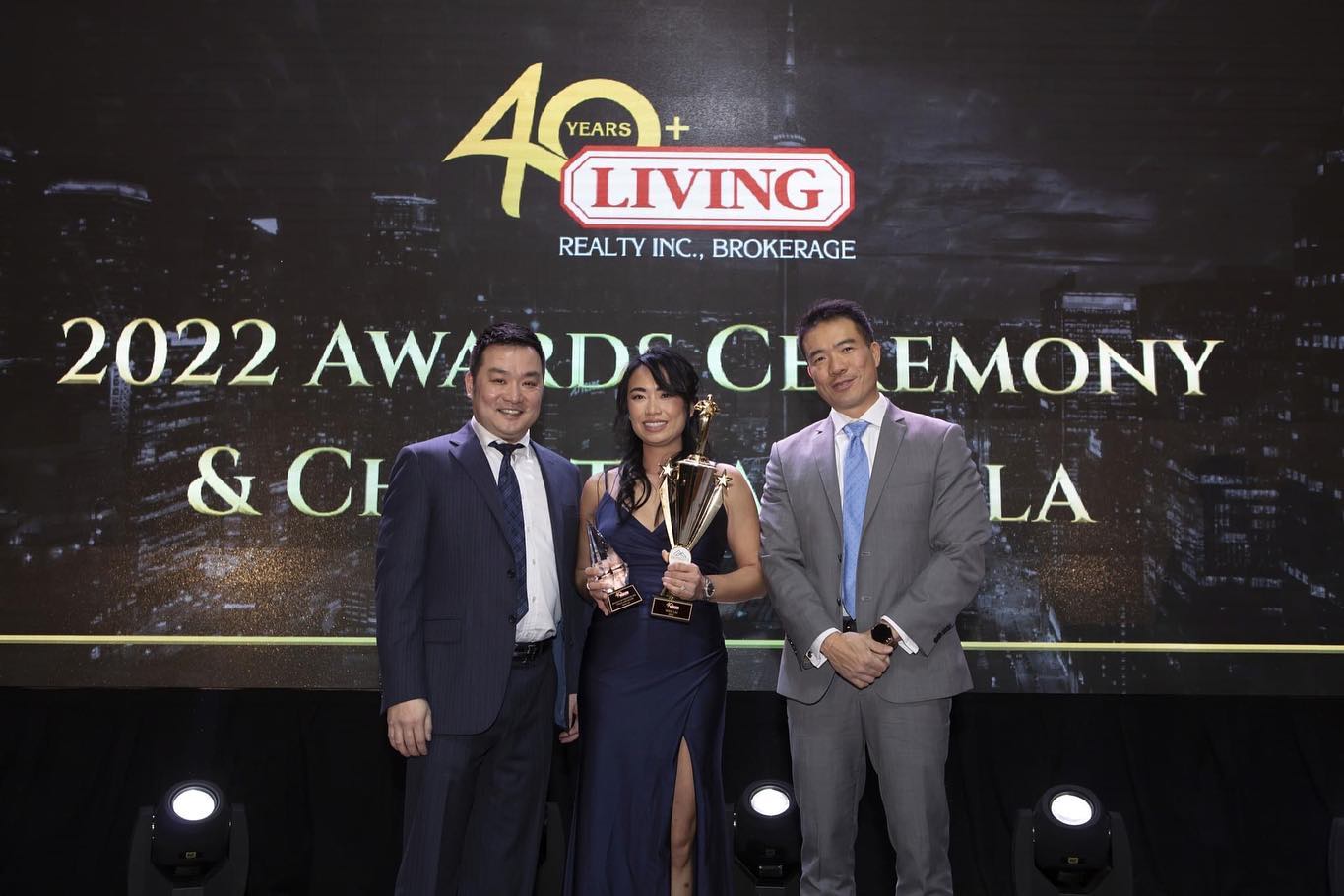 Wins Lai holding awards at 2022 Living Realty Top Producer ceremony.