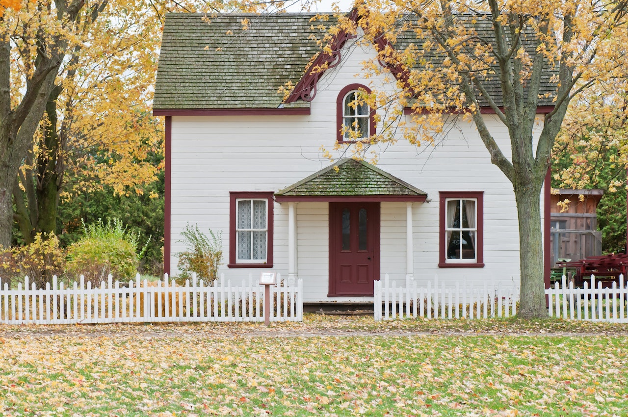 Photo of cute house in autumn with tree, leaves and foliage. 