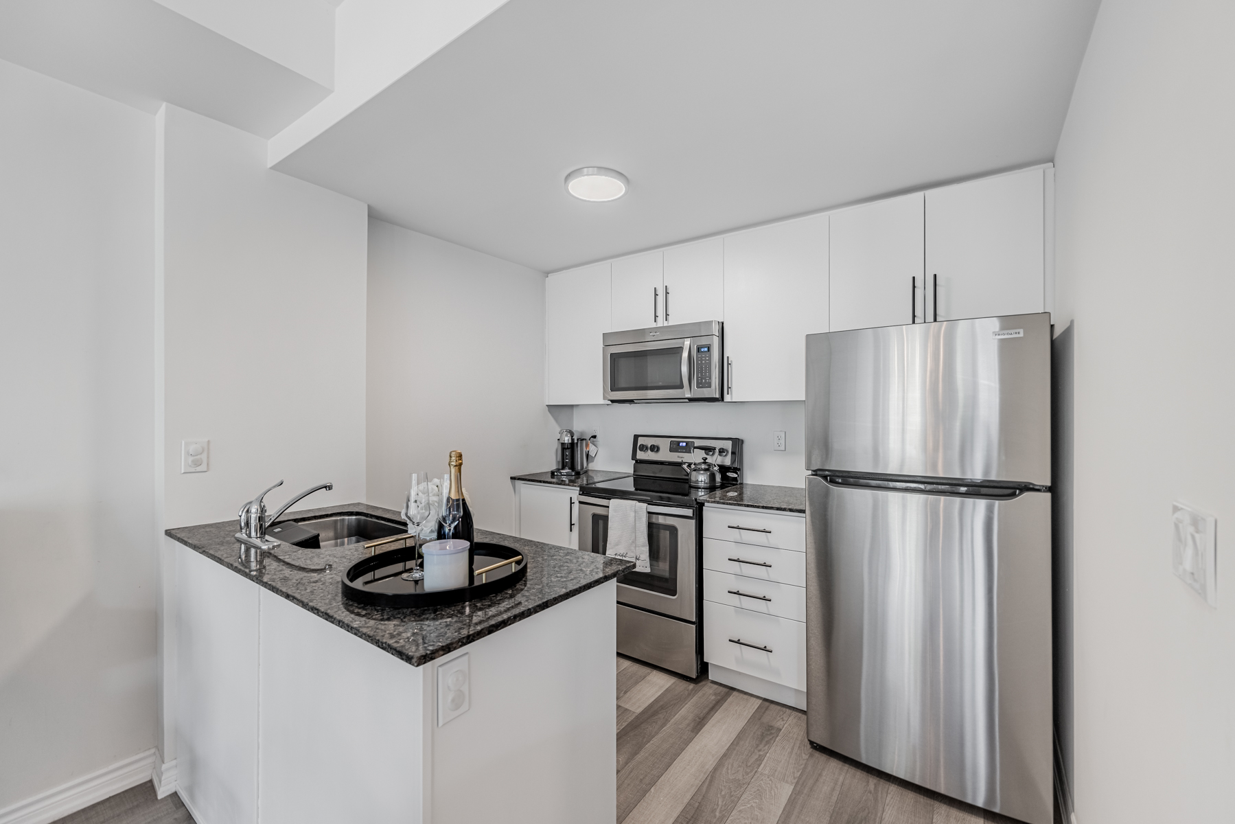 Modern kitchen with dark granite counters and multiple cabinets.