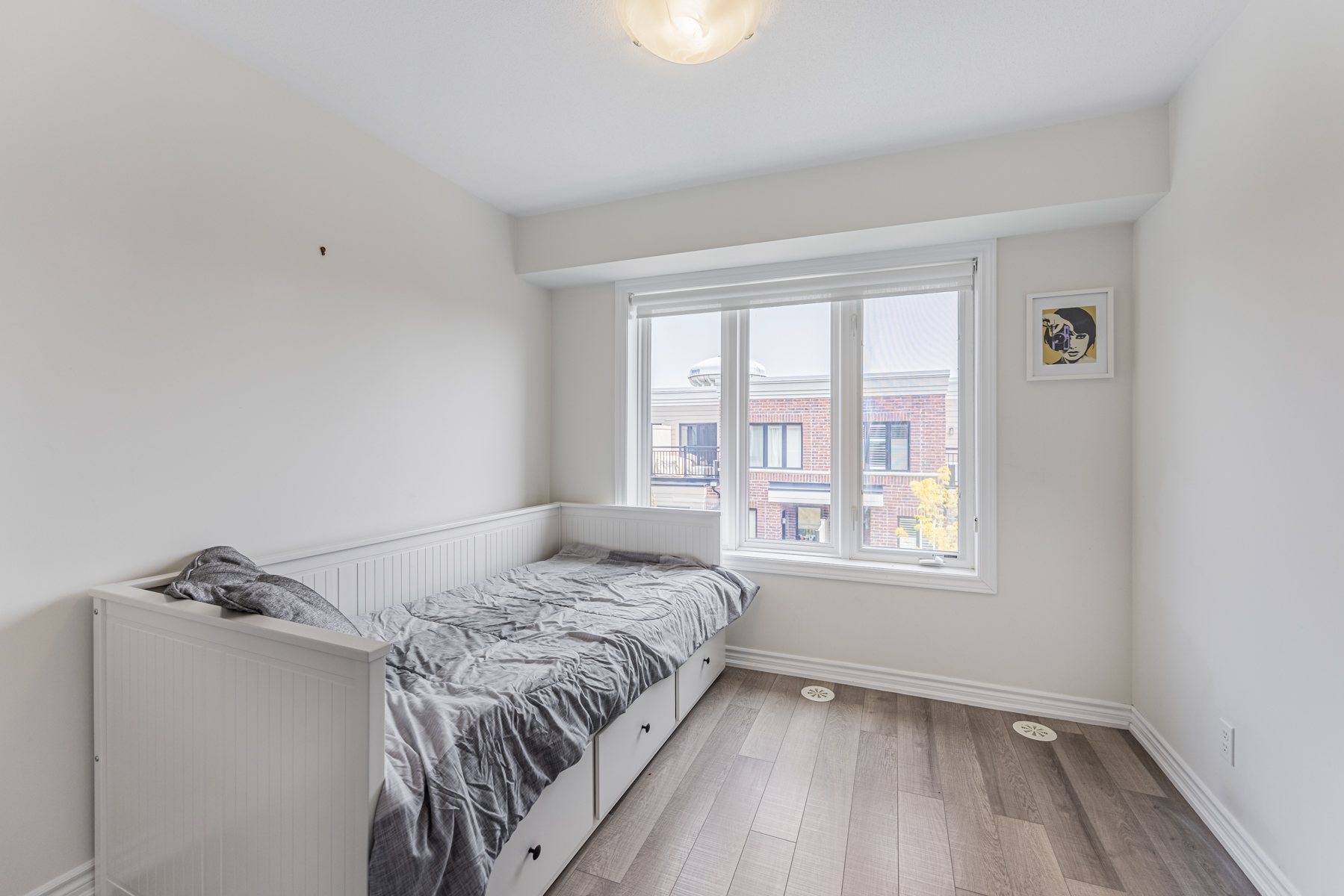 Bedroom with bed, vinyl floors and large windows.