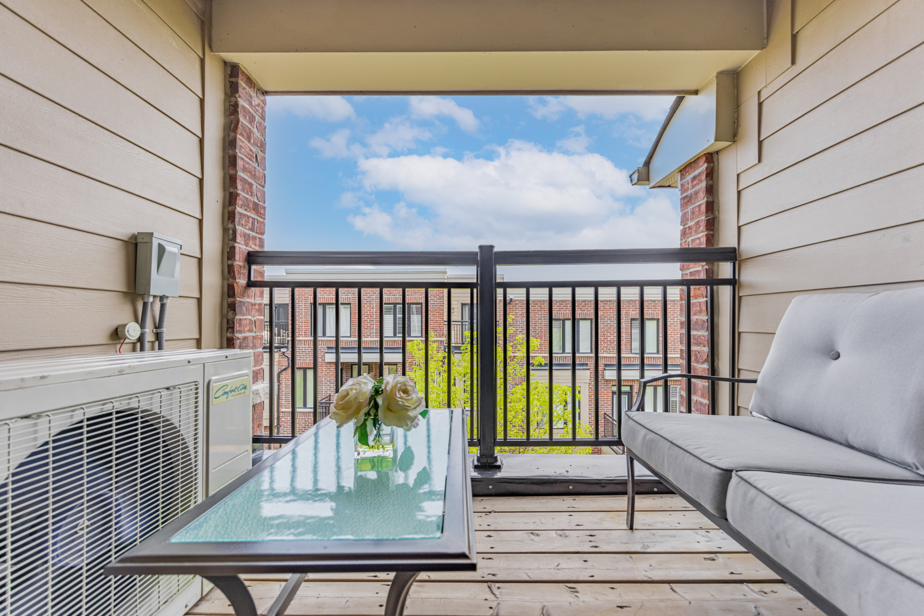 Spacious townhouse balcony with iron rails, wood floors and red-brick accents.