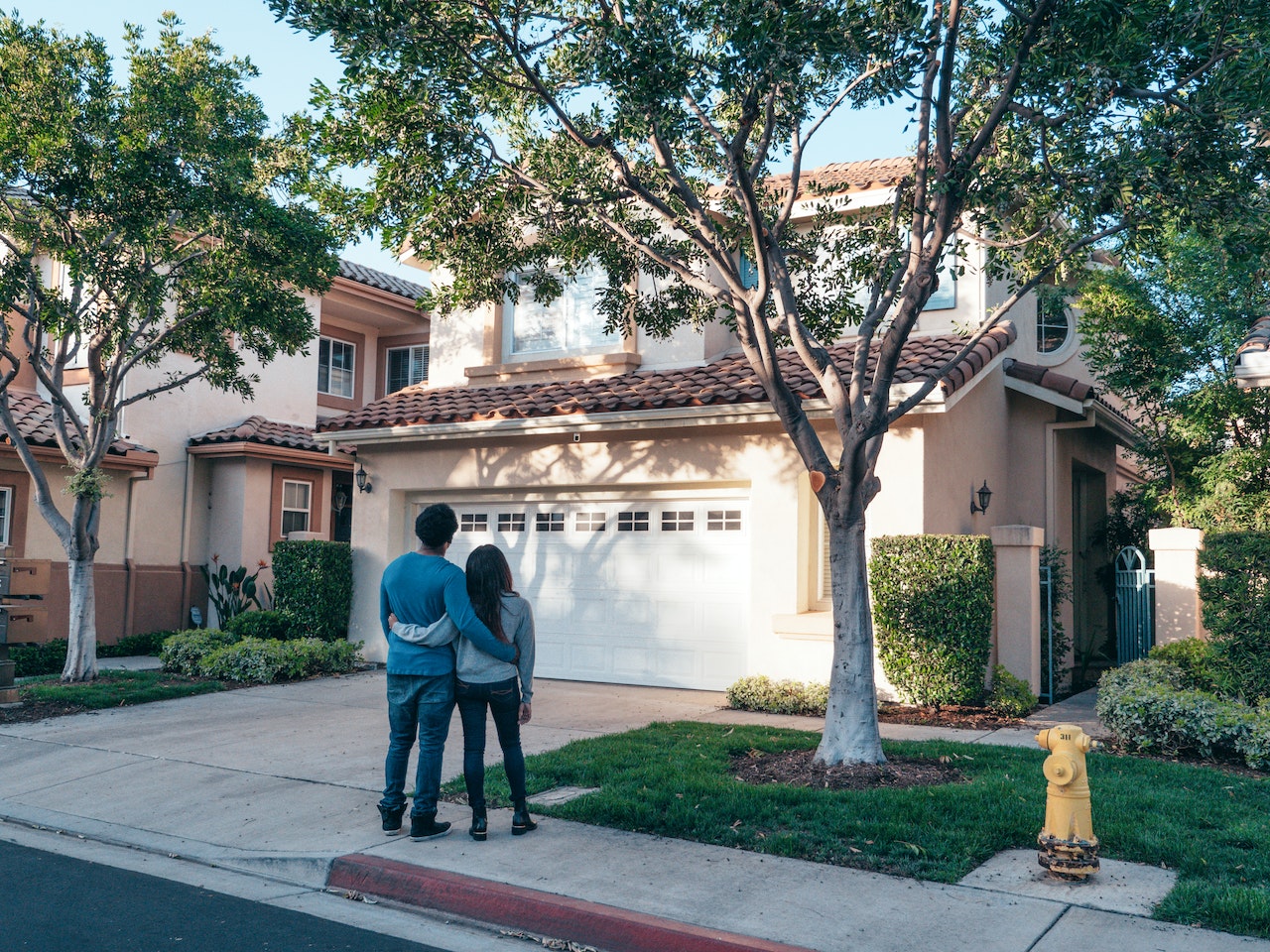 Young couple standing on sidewalk looking at house to show benefits of FHSA.