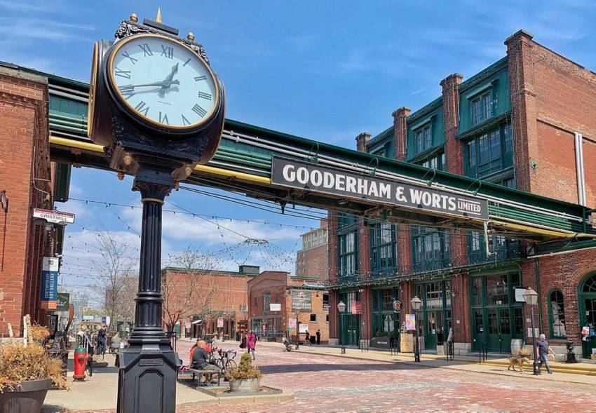 Antique clock, historic buildings, and Gooderham and Worts sign in Toronto's Distillery District.