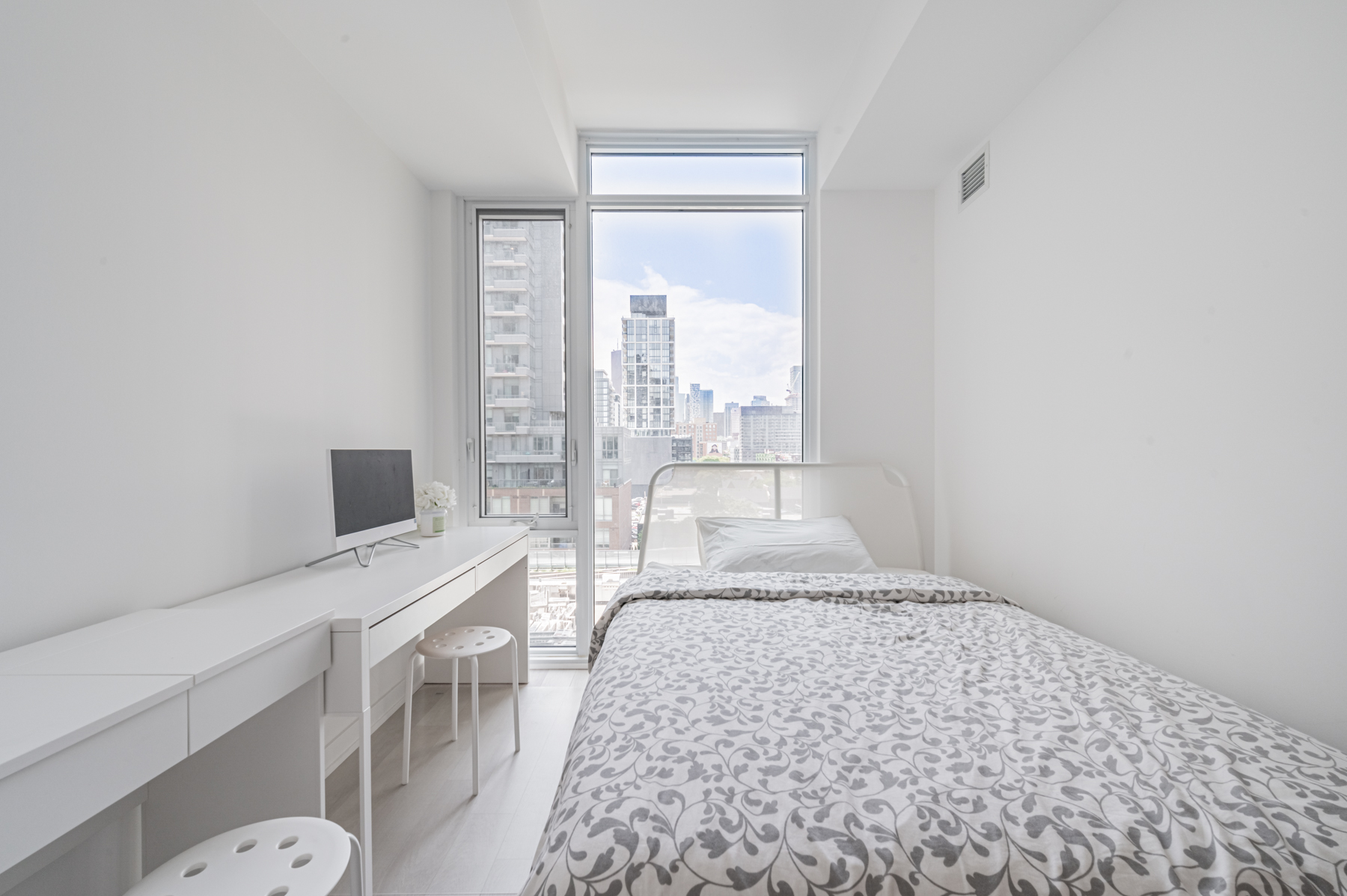 Condo bedroom with tall floor-to-ceiling windows with view of Toronto.