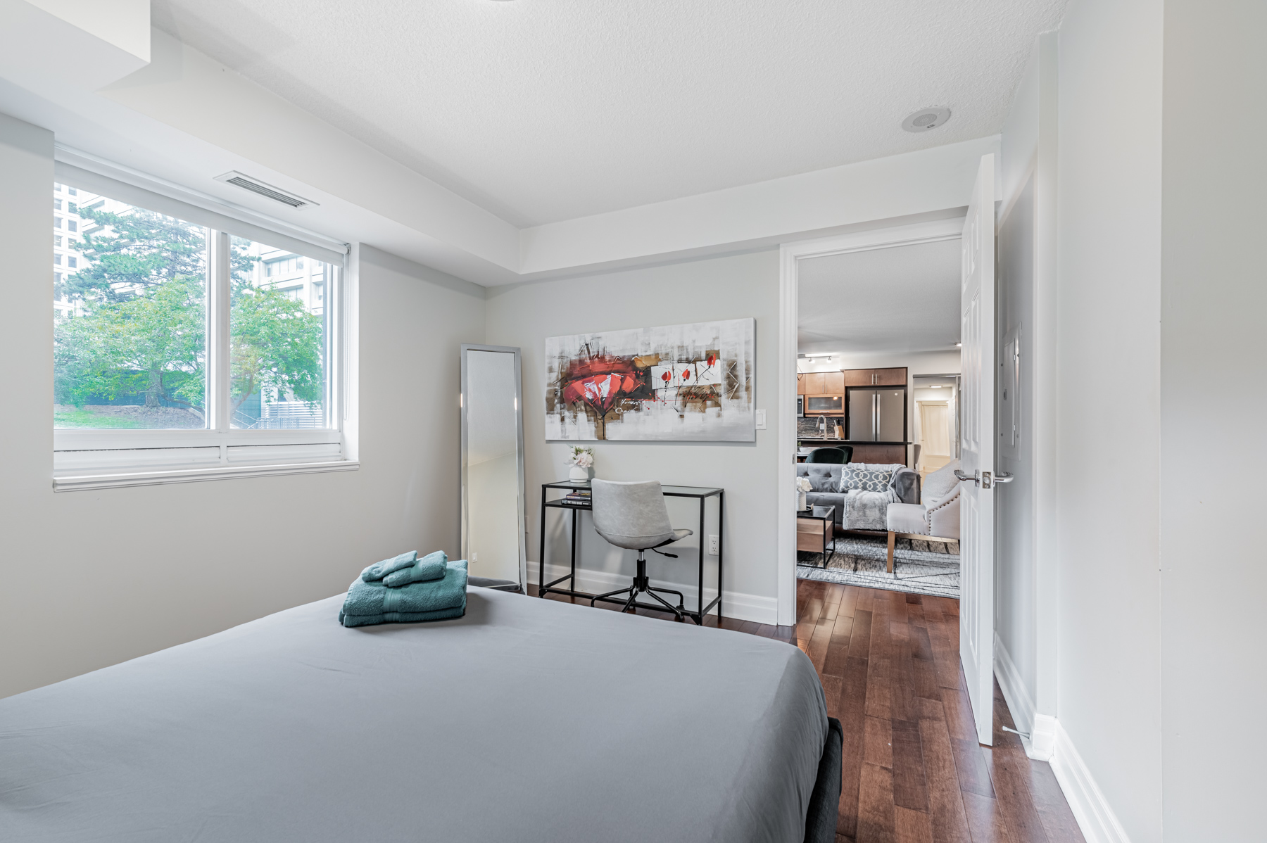 Naturally lit bedroom with hardwood floors and gray walls.